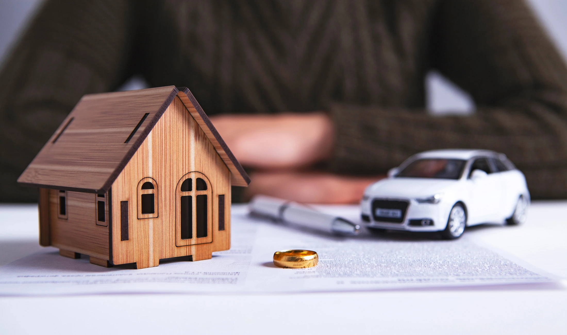 A tiny house, tiny car, and wedding ring sitting on top of a divorce decree. If you’re going through a divorce and you have assets, a Houston property division lawyer can help you.